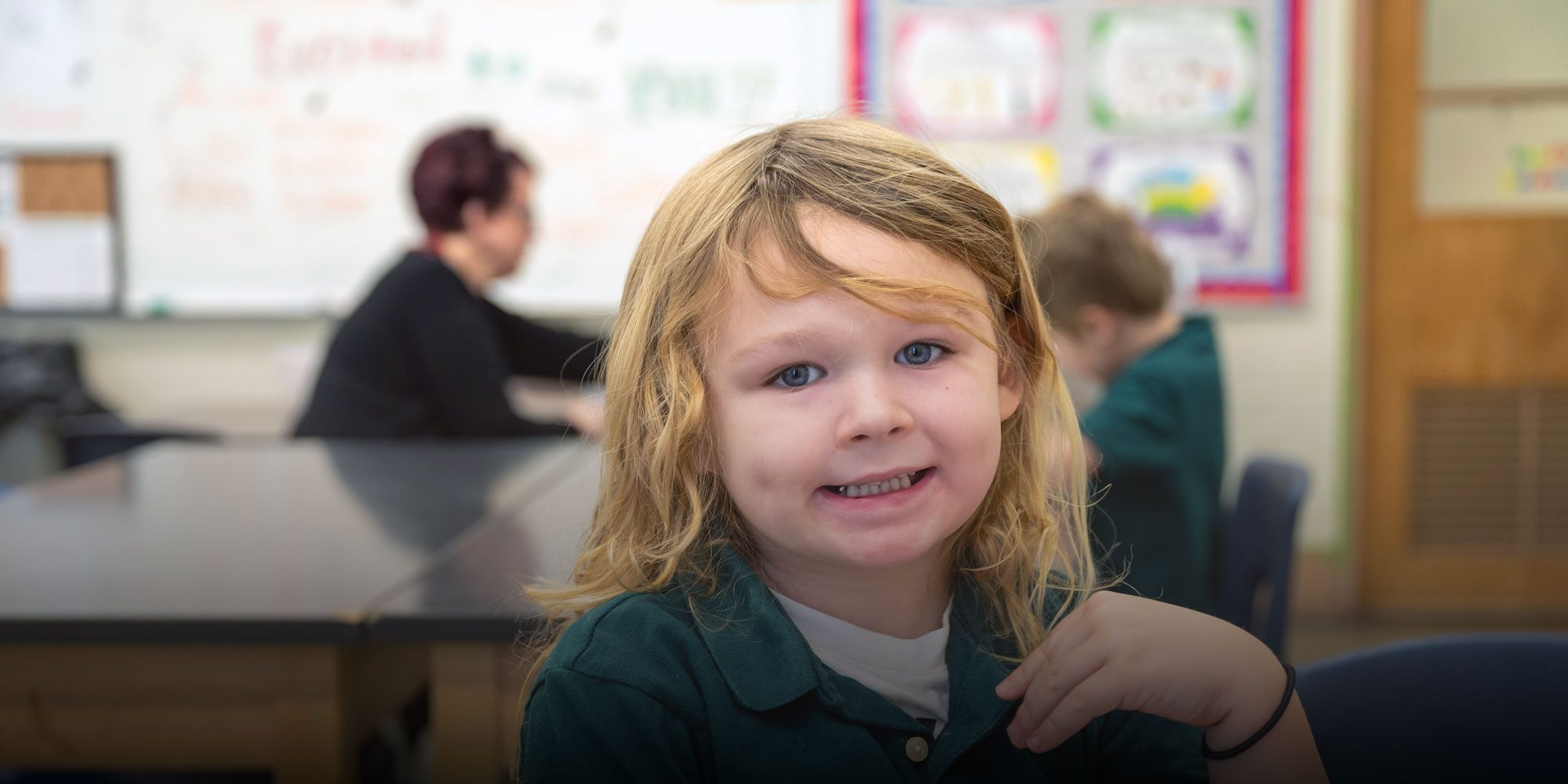 Smiling elementary student sitting at a classroom table.